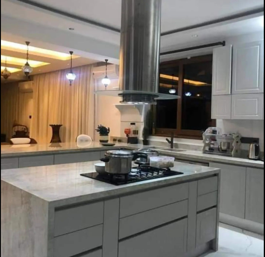 Grey island kitchen with a stainless-steel extractor hood and warm evening lighting